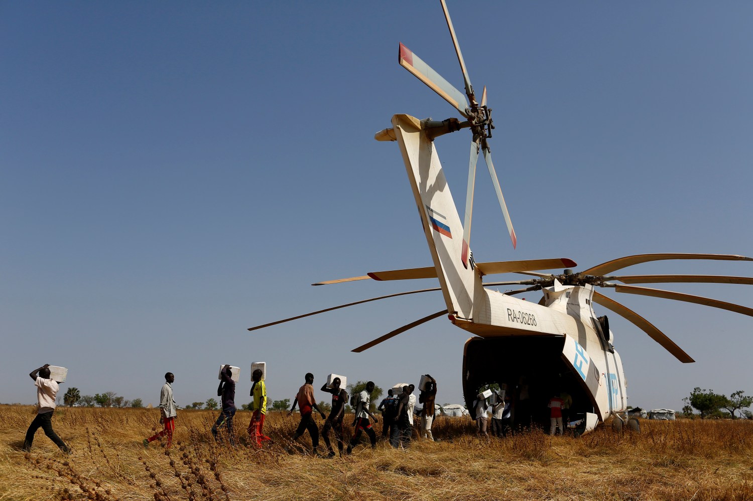 Men unload boxes of nutritional supplements from an helicopter prior to a humanitarian food distribution