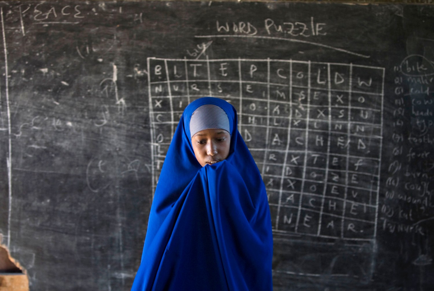 Somali refugee girl walks in front of a blackboard at Hagadera camp in Dadaab in northeastern Kenya