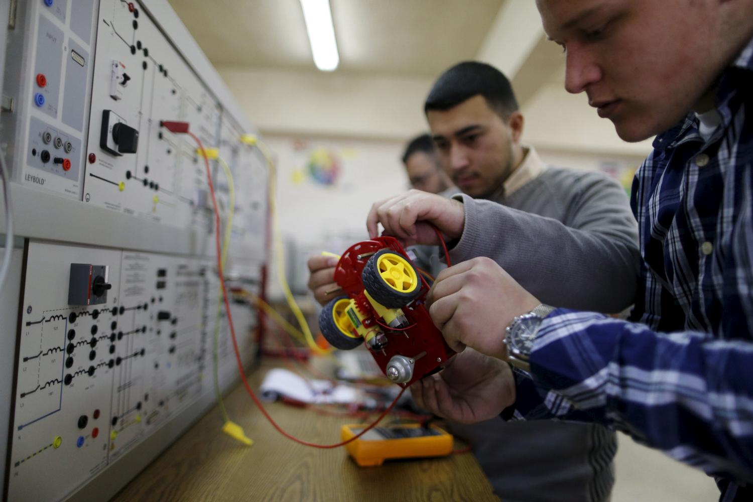 Palestinian students check a small electronic car that they control by an electronic glove they developed, at Birzeit University in the West Bank town of Birzeit January 21, 2016. Three Palestinian student developed the electronic glove that can be used to control several devices, including laptops and robots, as part of their graduation project. REUTERS/Ammar Awad