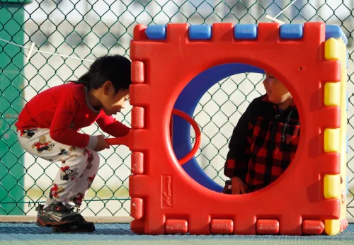 Four-year olds Ryan Htut (L) and Justin Hernandez play in a plastic cube at the Frederick, Maryland Head Start facility March 13, 2012.