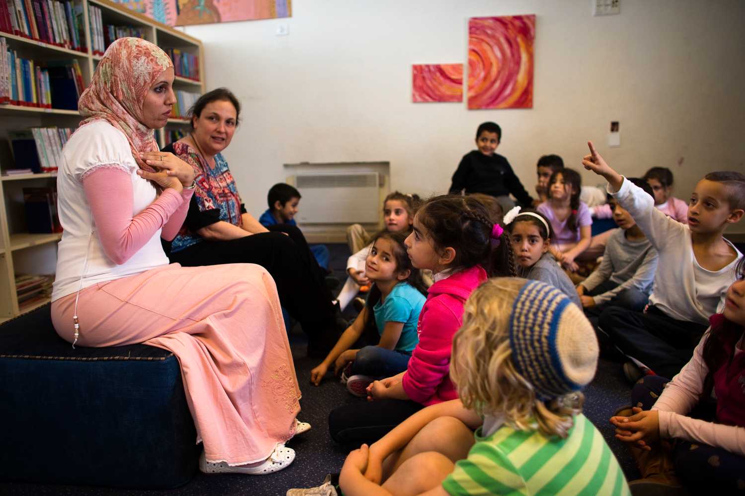 Alia Tunisi (L) and Sharon Suval (2nd L), first grade school teachers, talk to their students during reading hour at the Hand in Hand Arab Jewish bilingual school in Jerusalem December 3, 2014. The Hand in Hand school in Jerusalem presents an almost too-perfect scene in a tense and divided city, where Jews and Arabs do daily business but rarely befriend one other. REUTERS/Ronen Zvulun