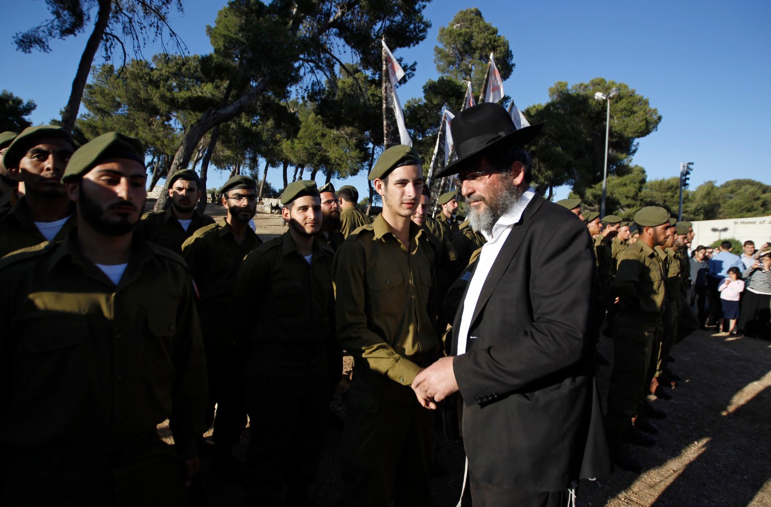 An ultra-Orthodox, or Haredi, Jewish man walks past Israeli soldiers of the Netzah Yehuda Haredi infantry battalion during their swearing-in ceremony in Jerusalem May 26, 2013, marking the end of their basic training in the Israeli Defense Forces. Israel clinched a deal on Wednesday to abolish wholesale exemptions from military service for Jewish seminary students, ending a brief crisis that divided the ruling coalition parties. Picture taken May 26, 2013. REUTERS/Ammar Awad (JERUSALEM - Tags: RELIGION MILITARY POLITICS)