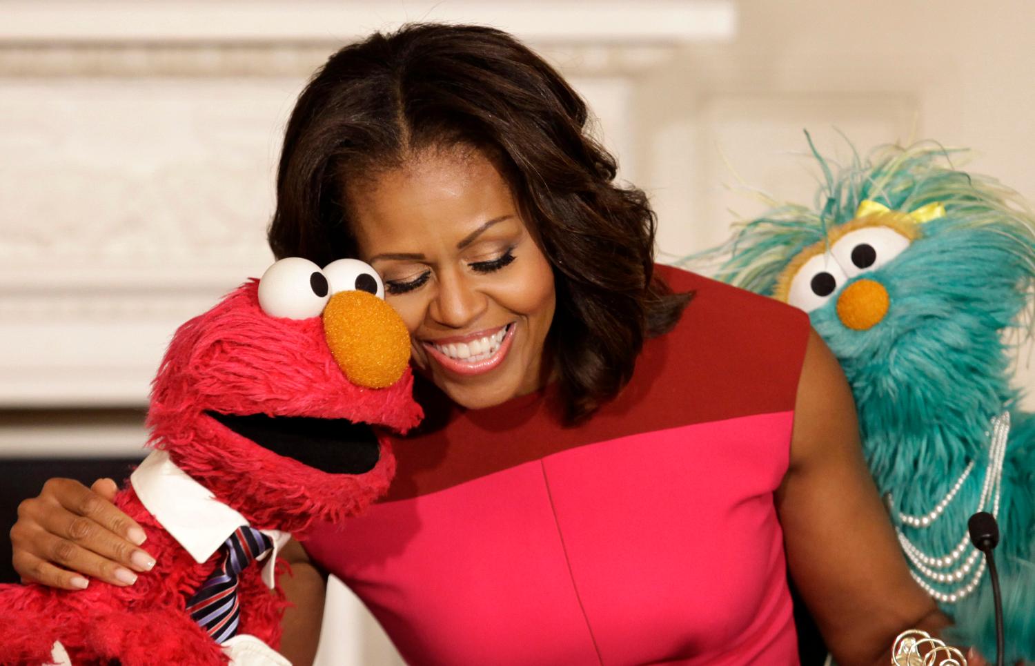 U.S. first lady Michelle Obama hugs PBS Sesame Street characters Elmo and Rosita after delivering remarks on marketing healthier foods to children at the White House in Washington