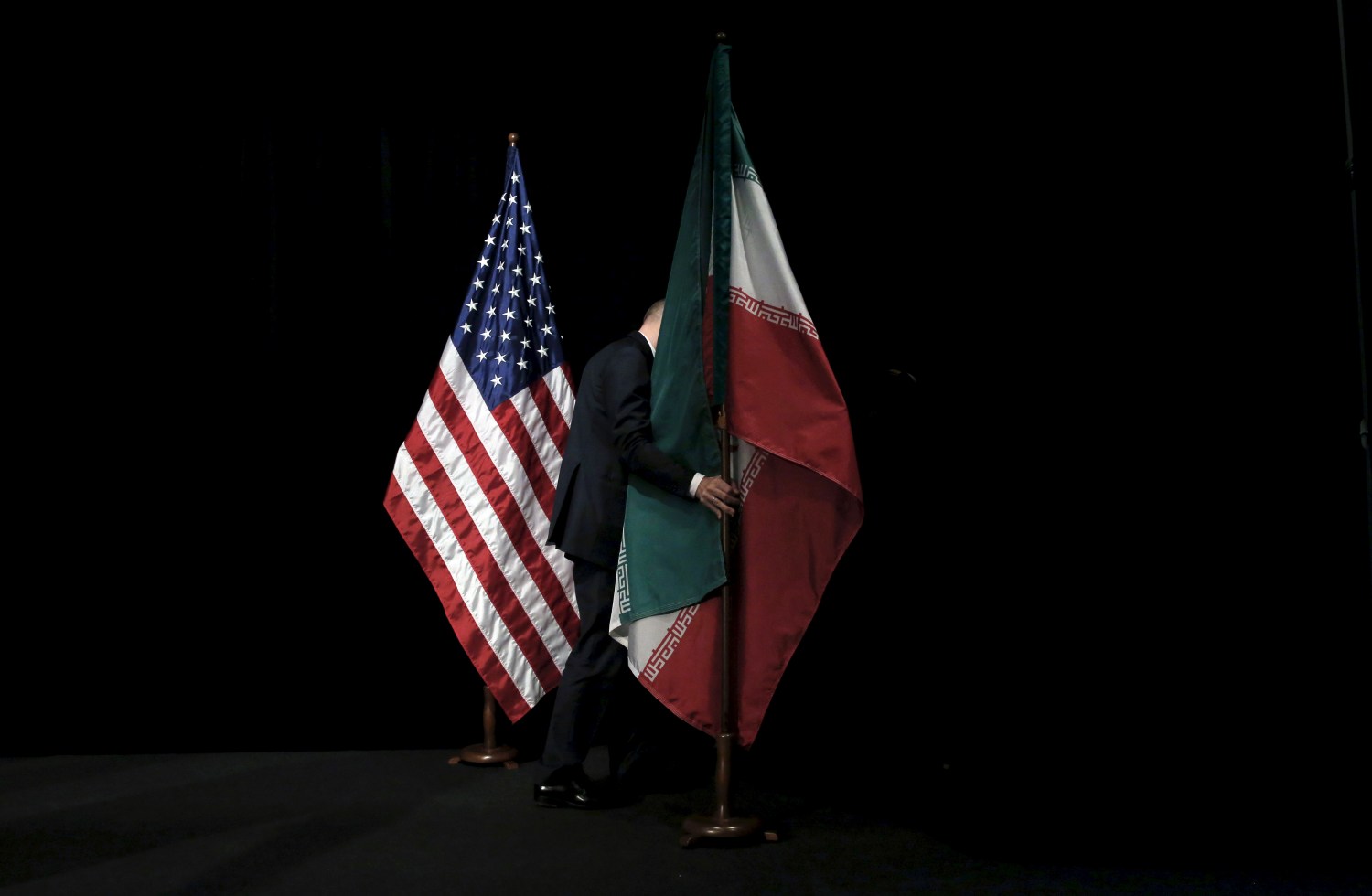 A staff removes the Iranian flag from the stage after a group picture with foreign ministers and representatives during the Iran nuclear talks at the Vienna International Center in Vienna