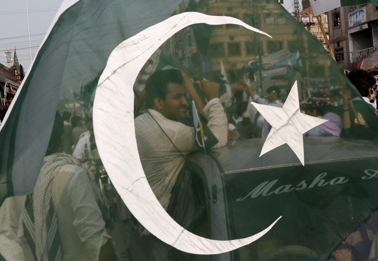 People wave flags and celebrate at a national day rally during the country's 69th Independence Day in Peshawar, Pakistan, August 14, 2015. REUTERS/Khuram Parvez - RTX1O9SO