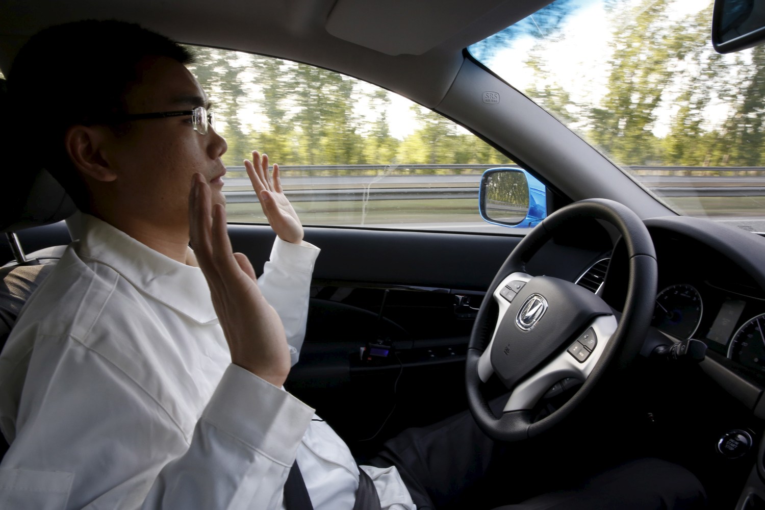 Li Zengwen, a development engineer at Changan Automobile, lifts his hands off the steering wheel as the car is on self-driving mode during a test drive on a highway in Beijing
