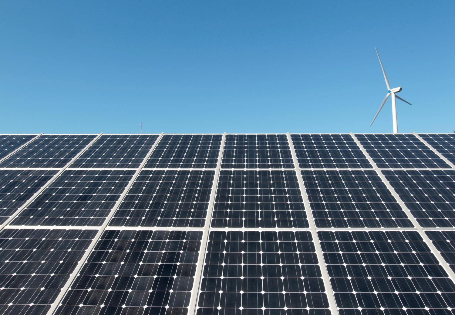 A wind turbine is seen over the panels of a solar power plant of Korea South East Power Co. (KOSEP) in Incheon, in this file photo taken September 30, 2010. REUTERS/Jo Yong-Hak/File Photo - RTX2UWTH