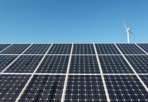 A wind turbine is seen over the panels of a solar power plant of Korea South East Power Co. (KOSEP) in Incheon, in this file photo taken September 30, 2010. REUTERS/Jo Yong-Hak/File Photo - RTX2UWTH