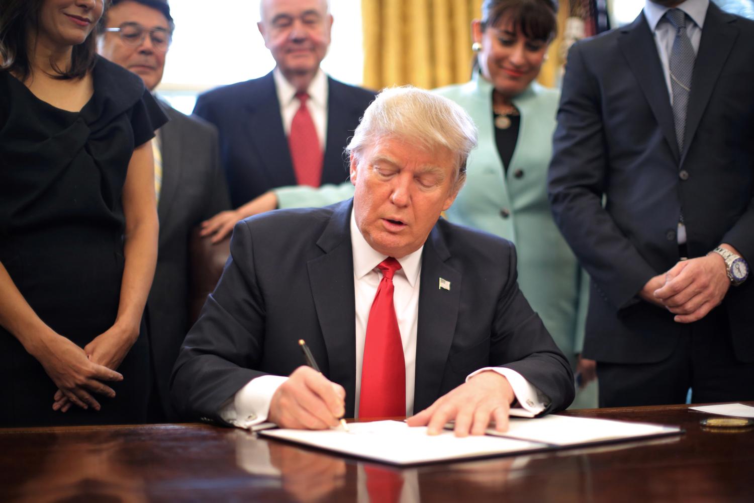 U.S. President Donald Trump signs an executive order cutting regulations, accompanied by small business leaders at the Oval Office of the White House in Washington U.S.