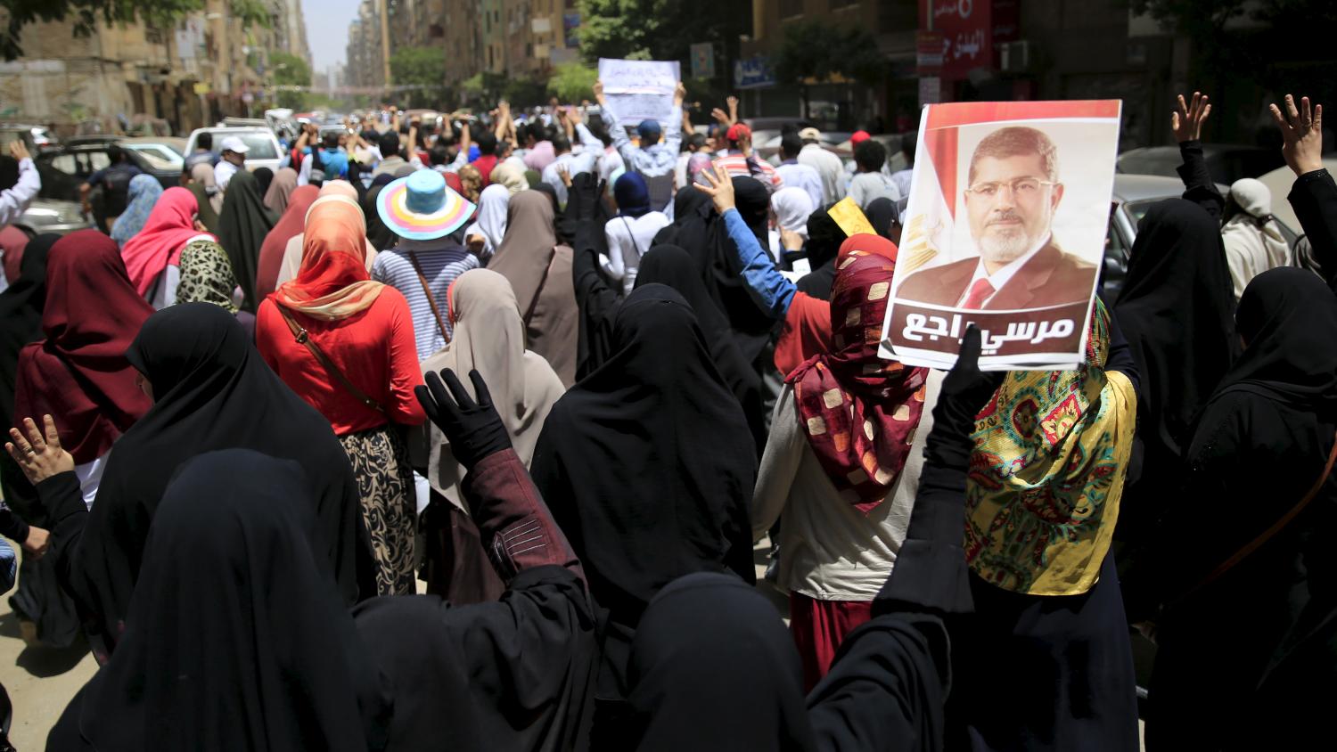 Supporters of the Muslim Brotherhood and deposed Egyptian President Mohamed Mursi shout slogans against an Egyptian court's decision to sentence Mursi and other leaders to death, at a rally in Al Haram street near Giza square, south of Cairo, Egypt June 19, 2015. Mursi will appeal against a conviction for violence, kidnapping and torture imposed by a court over the killing of protesters, his lawyers were quoted as saying by state media on Thursday. The poster of Mursi reads, "Mursi will back." REUTERS/Amr Abdallah Dalsh - RTX1H98A