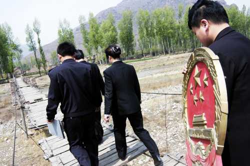 Chinese mobile court officials walk towards a village to convene a court in Zuoquan County, north China's Shanxi province, May 10, 2005. Two mobile courts were established in August 2002 in Zuoquan to serve the local people in remote and mountainous regions. According to China's law, the national emblem shall be hung in the courtrooms of the people's courts at various levels. Picture taken on May 10, 2005. CHINA OUT REUTERS/China Newsphoto SUN/TZ - RTRAQVR