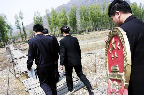 Chinese mobile court officials walk towards a village to convene a court in Zuoquan County, north China's Shanxi province, May 10, 2005. Two mobile courts were established in August 2002 in Zuoquan to serve the local people in remote and mountainous regions. According to China's law, the national emblem shall be hung in the courtrooms of the people's courts at various levels. Picture taken on May 10, 2005. CHINA OUT REUTERS/China Newsphoto SUN/TZ - RTRAQVR