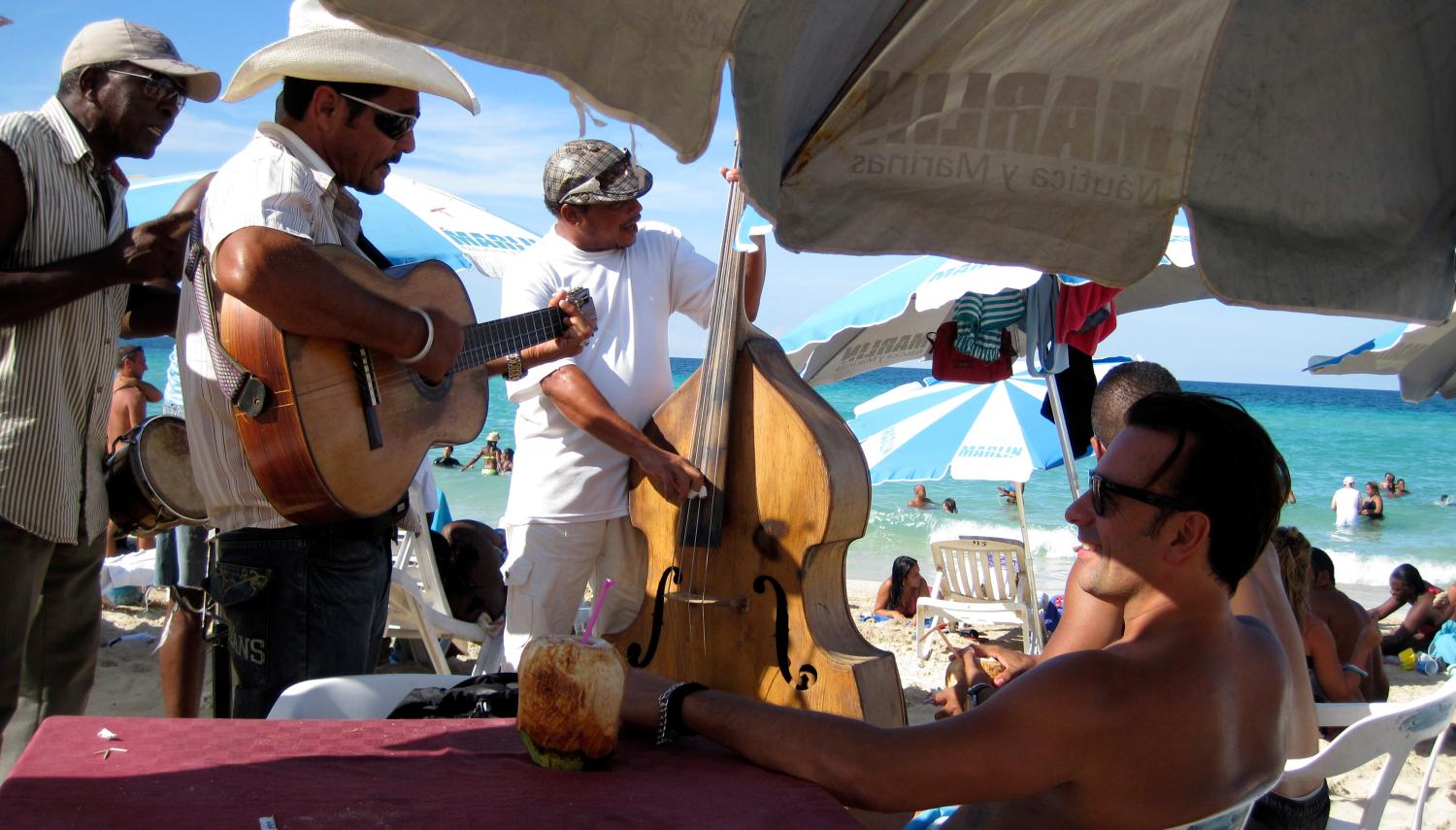 Tourists listen to a live band as they enjoy a day on the beach on the outskirts of Havana September 30, 2012. Cuba's beaches are an attraction for tourists the world over, whether they are foreigners paying thousands of dollars to reach them, or Cubans paying as little as five dollars for a three-day vacation in a seaside cabin. REUTERS/Desmond Boylan (CUBA - Tags: SOCIETY TRAVEL) - RTR38N3S