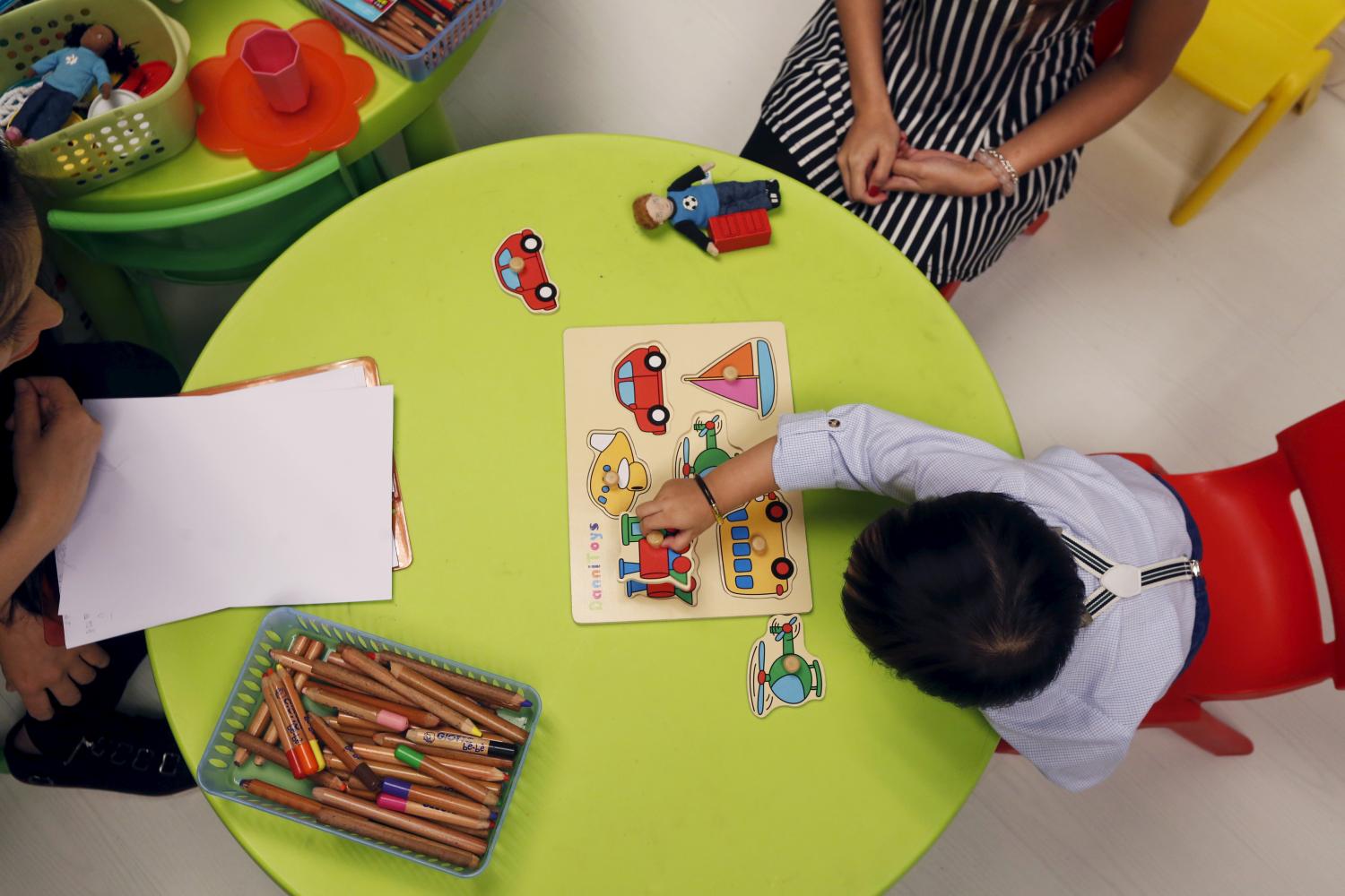 Two-year-and-three-month-old Carlson Chuen undertakes a test of identifying objects during a mock interview, as part of a specialized class preparing toddlers for kindergarten.