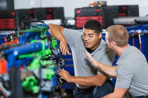 Two young men in vocational school, taking a class on repairing diesel engines.