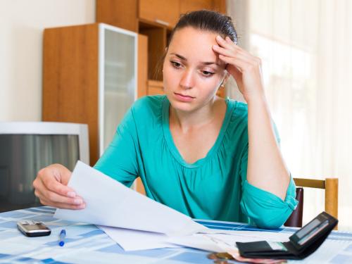 Thoughtful young woman sitting at home depressed because of bills