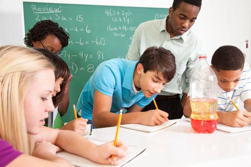 Multi-ethnic group of students, African descent teacher in science class They are taking a review quiz after doing an experiment.