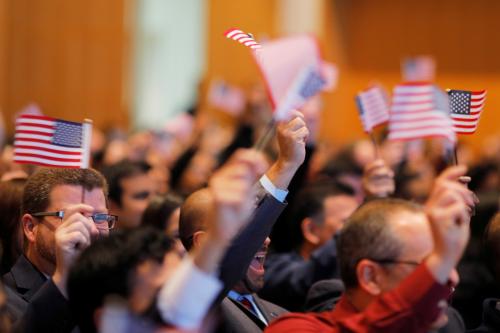 New U.S. citizens wave U.S. flags during a citizenship ceremony.