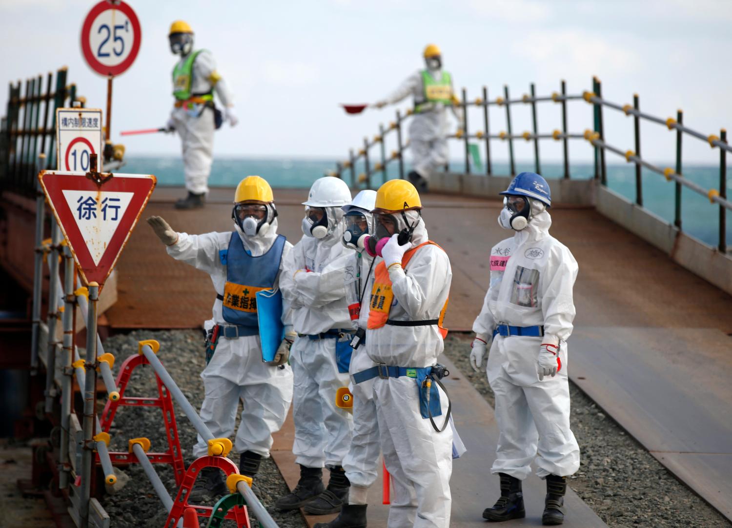 Workers, wearing protective suits and masks, are seen near the No. 3 and No.4 reactor buildings at Tokyo Electric Power Co's (TEPCO) tsunami-crippled Fukushima Daiichi nuclear power plant in Okuma town, Fukushima prefecture, Japan February 10, 2016. REUTERS/Toru Hanai - RTX26AMM
