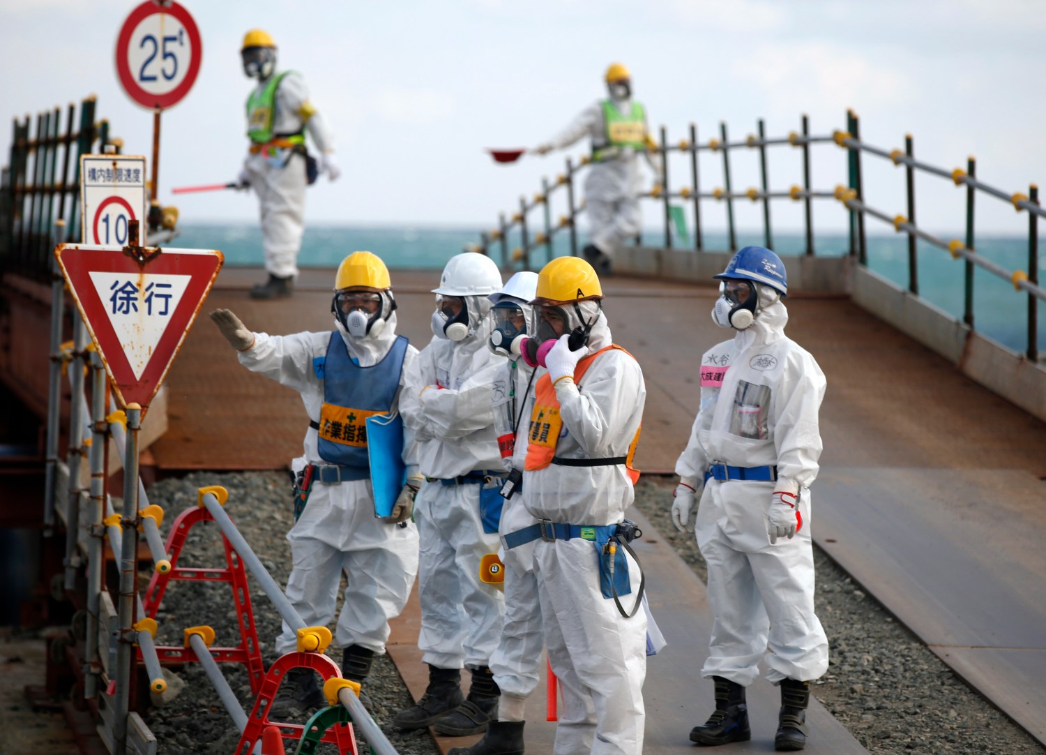 Workers, wearing protective suits and masks, are seen near the No. 3 and No.4 reactor buildings at Tokyo Electric Power Co's (TEPCO) tsunami-crippled Fukushima Daiichi nuclear power plant in Okuma town, Fukushima prefecture, Japan February 10, 2016. REUTERS/Toru Hanai - RTX26AMM