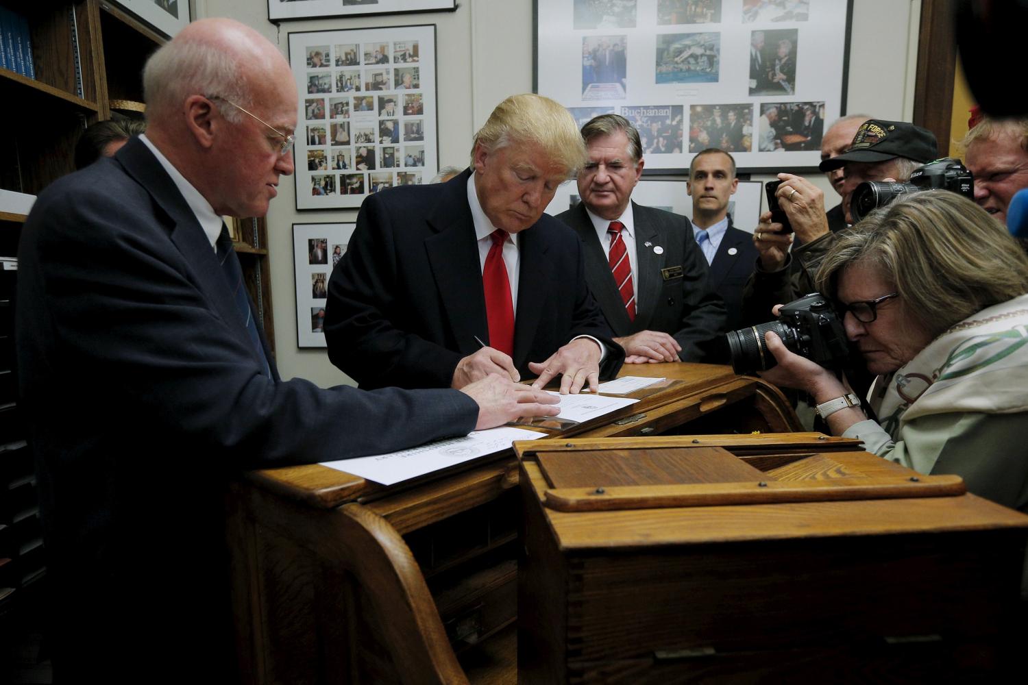 New Hampshire Secretary of State William Gardner (L) watches as U.S. Republican presidential candidate Trump signs his declaration of candidacy to appear on the New Hampshire primary ballot in Concord, New Hampshire, November 4, 2015. REUTERS/Brian Snyder - RTX1UQWO