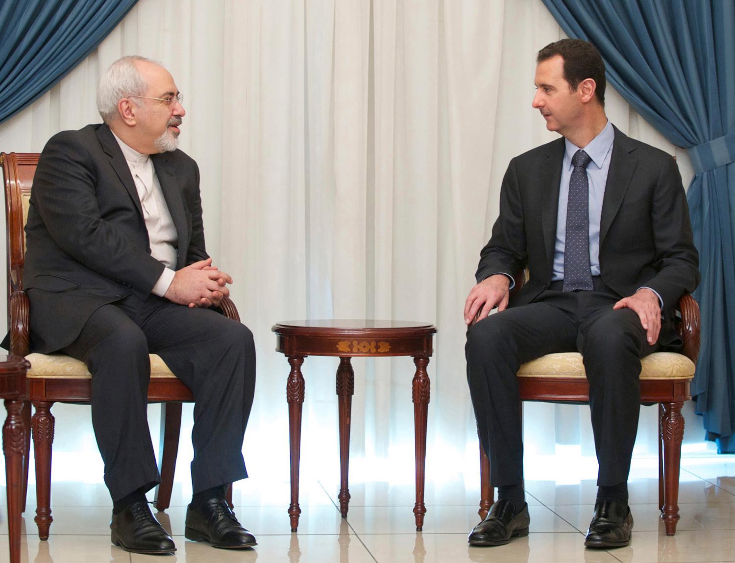 Syria's President Bashar al-Assad (R) meets Iran's Foreign Minister Mohammad Javad Zarif in Damascus January 15, 2014, in this handout released by Syria's national news agency SANA. REUTERS/SANA/Handout via Reuters (SYRIA - Tags: POLITICS CONFLICT) ATTENTION EDITORS - THIS IMAGE WAS PROVIDED BY A THIRD PARTY. FOR EDITORIAL USE ONLY. NOT FOR SALE FOR MARKETING OR ADVERTISING CAMPAIGNS. THIS PICTURE IS DISTRIBUTED EXACTLY AS RECEIVED BY REUTERS, AS A SERVICE TO CLIENTS