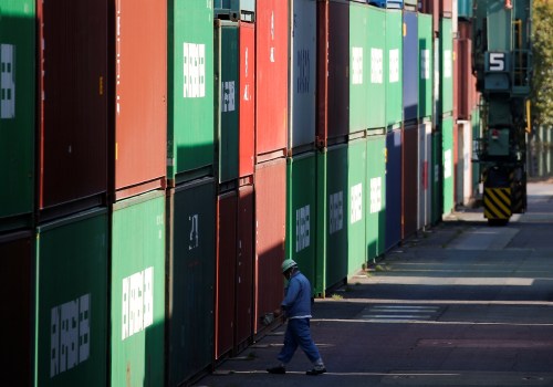 A worker walks between shipping containers at a port in Tokyo