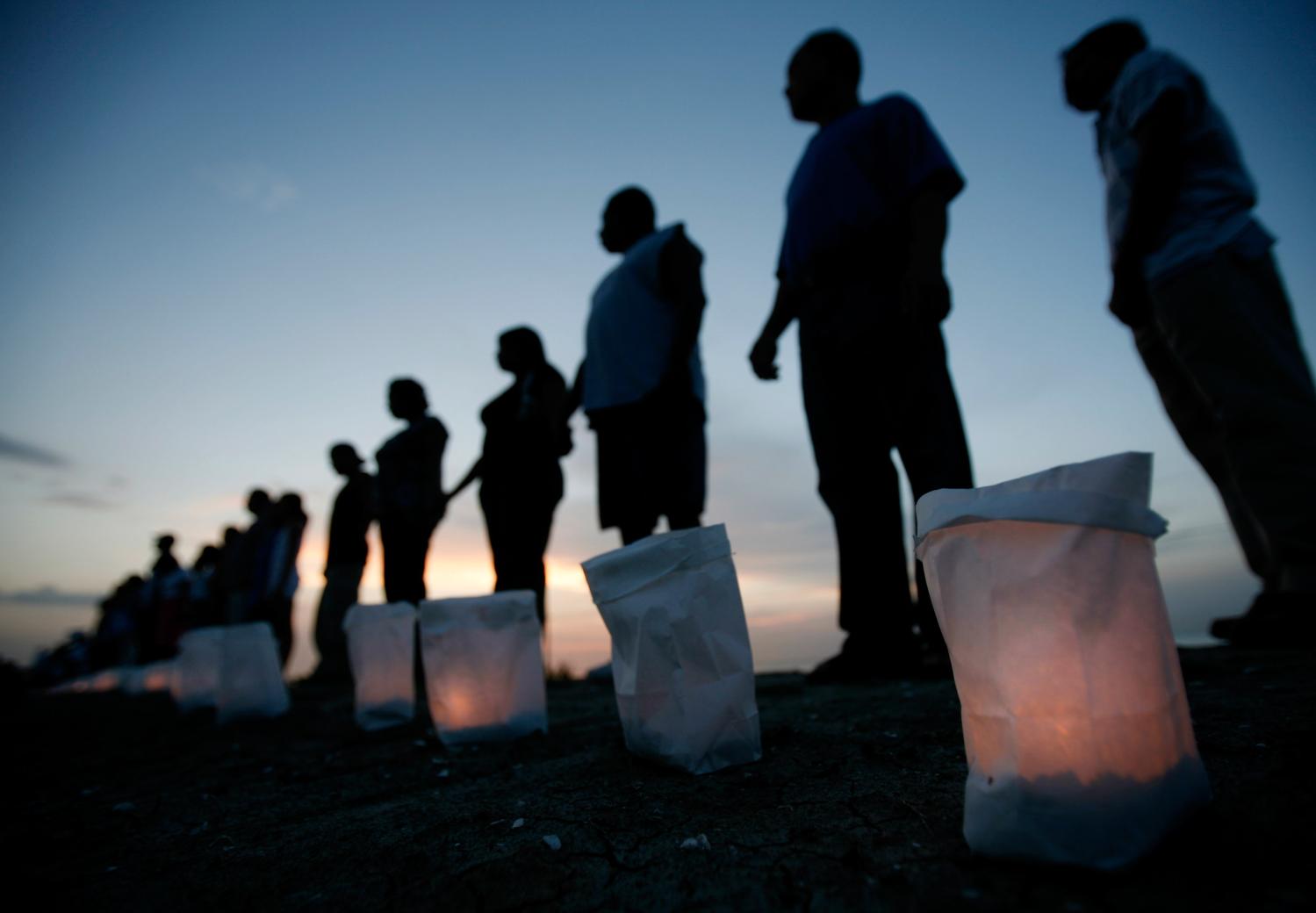 New Orleans residents stand during a candlelight ceremony dedicated to the victims and survivors of Hurricane Katrina on the levee in Orleans Parish August 28, 2006, nearly a year after the hurricane struck.