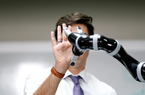 Canadian Prime Minister Justin Trudeau high fives a robotic arm as he takes part in a robotics demonstration at Kinova Robotics in Boisbriand, Quebec