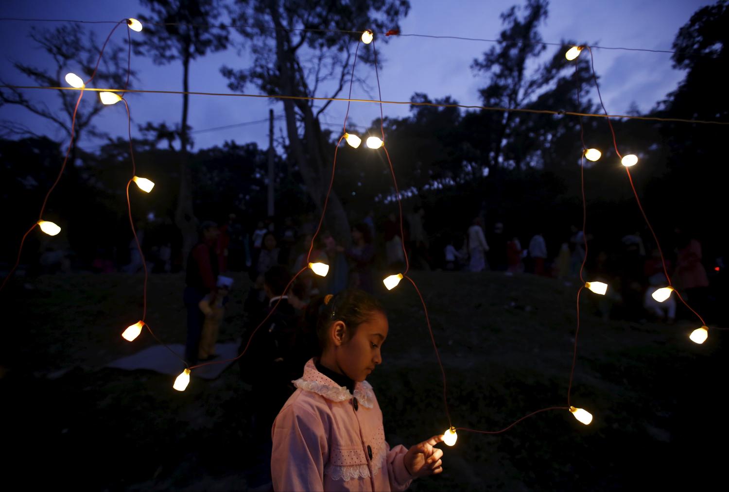 A girl plays with a light bulb along the bank of Bagmati River during the "Chhat" festival in Kathmandu