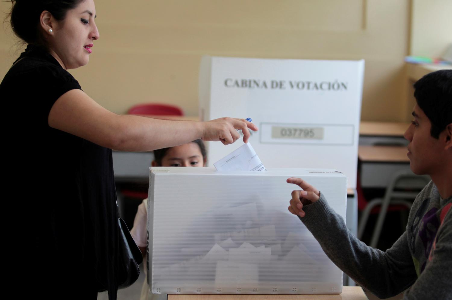 A woman deposits her vote in a ballot box in Peru's presidential election at a polling station in Lima