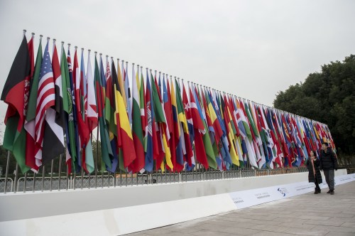People walk in front of national flags which are set up for the upcoming 2nd World Internet Conference in Jiaxing