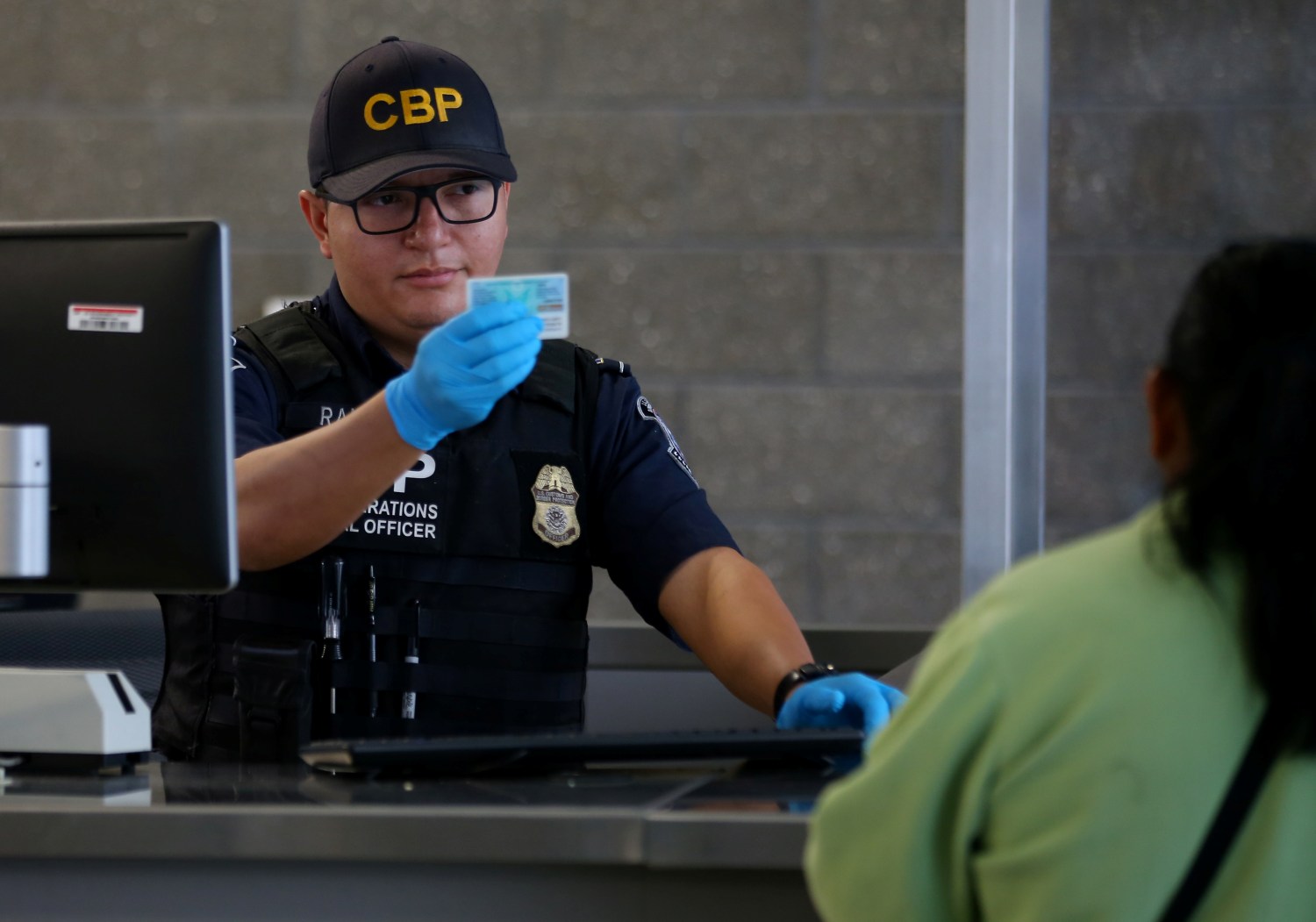 A U.S. Customs and Border Patrol officer interviews people entering the United States from Mexico at the border crossing in San Ysidro