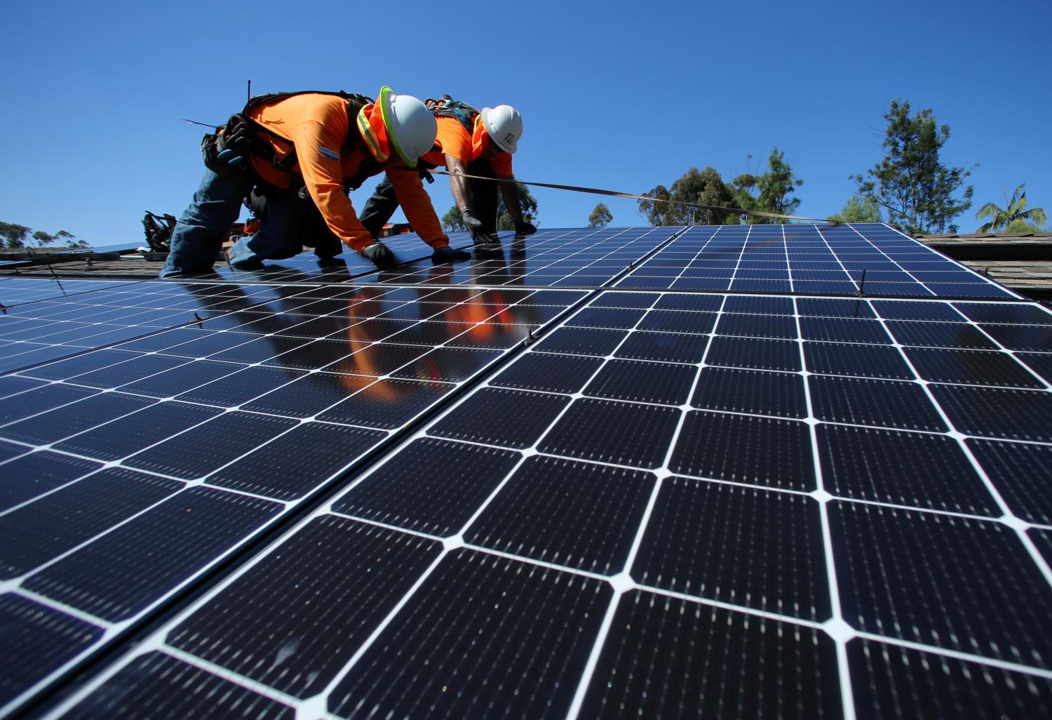 Solar installers from Baker Electric place solar panels on the roof of a residential home in Scripps Ranch, San Diego, California