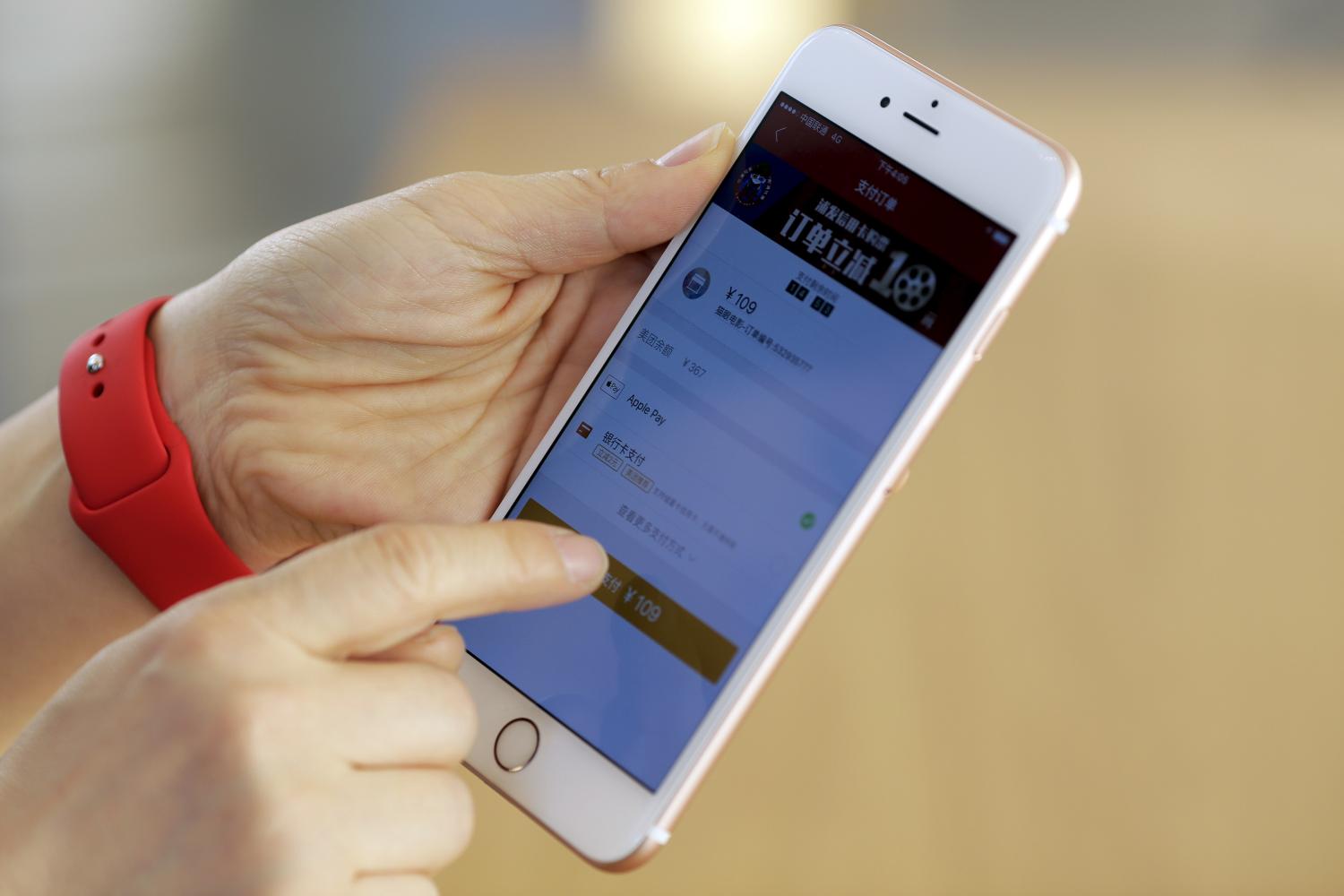 An employee uses an Apple iPhone to demonstrate the Apple Pay service in Beijing