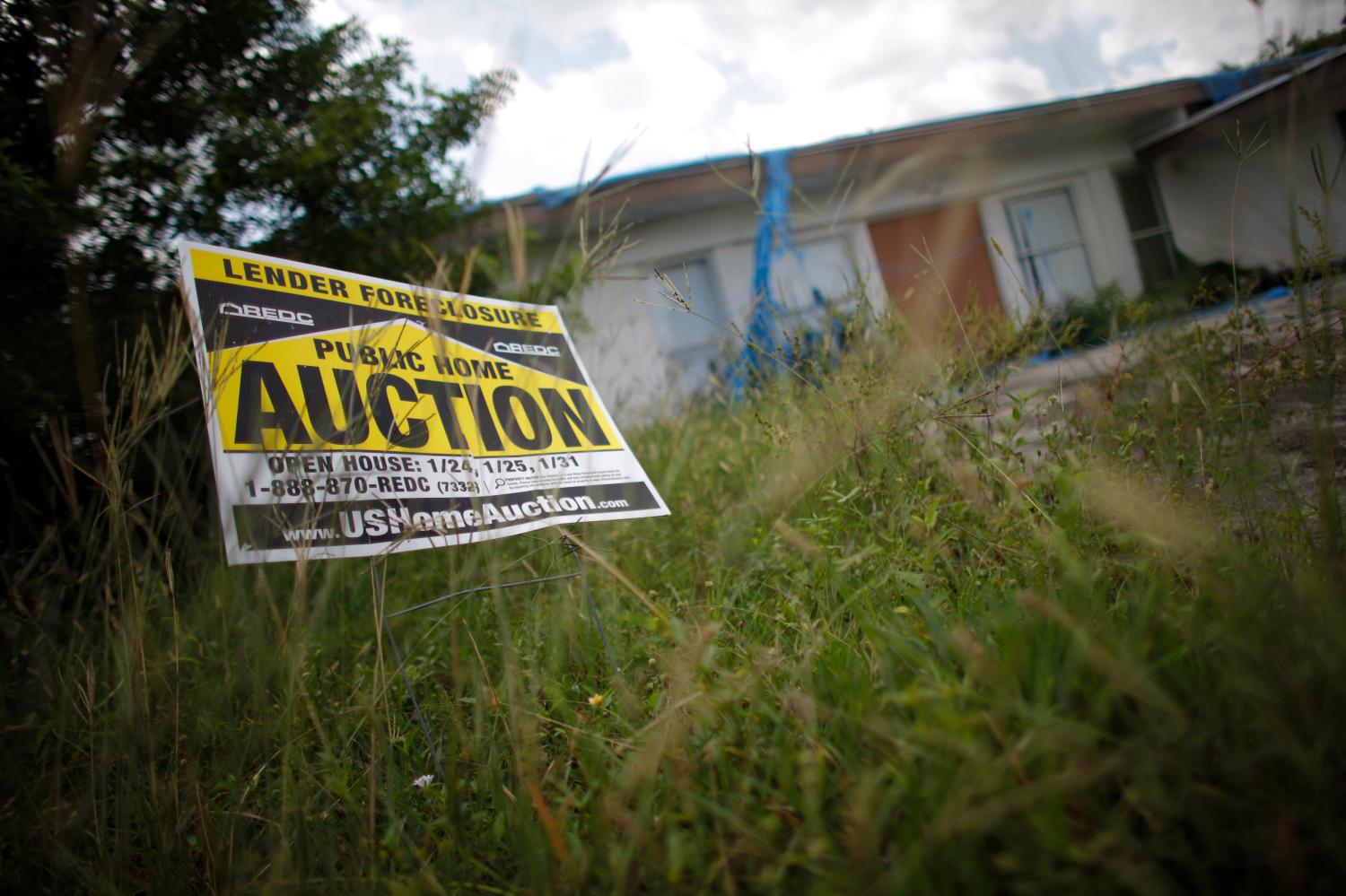 An auction sign for a property is seen at the front garden of a foreclosed house in Miami Gardens
