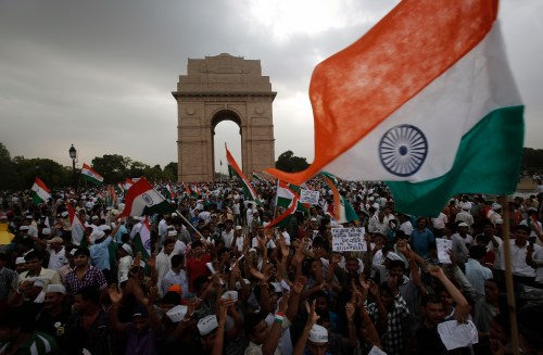 Supporters of veteran Indian social activist Hazare wave India's national flags at the India Gate during a hunger strike by Hazare and his team members in New Delhi
