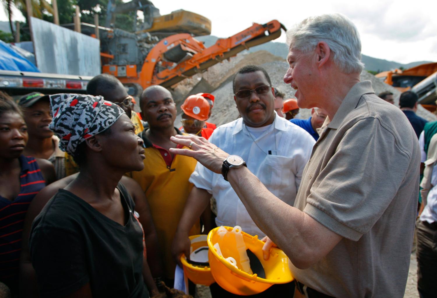 Former U.S. President Bill Clinton speaks with residents as he visits a project of the United Nations Development Program (UNDP) to recycle debris in Port-au-Prince