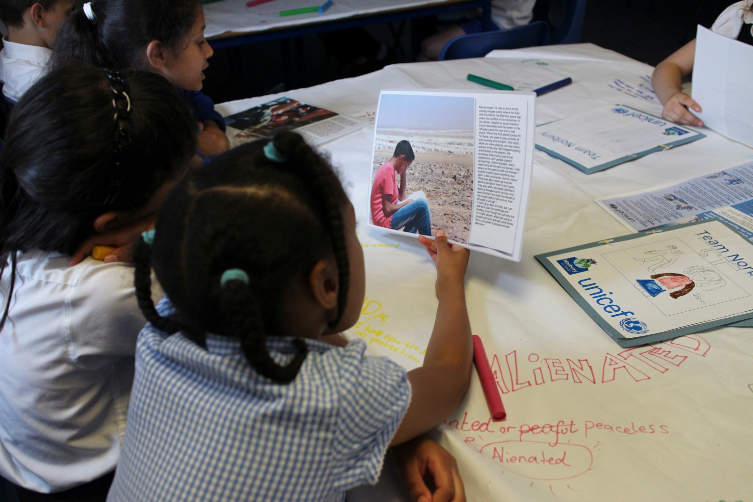 Primary school children, including those with refugee backgrounds, read real-life stories about refugees during a classroom lesson about the refugee crisis at Norbury School in Harrow