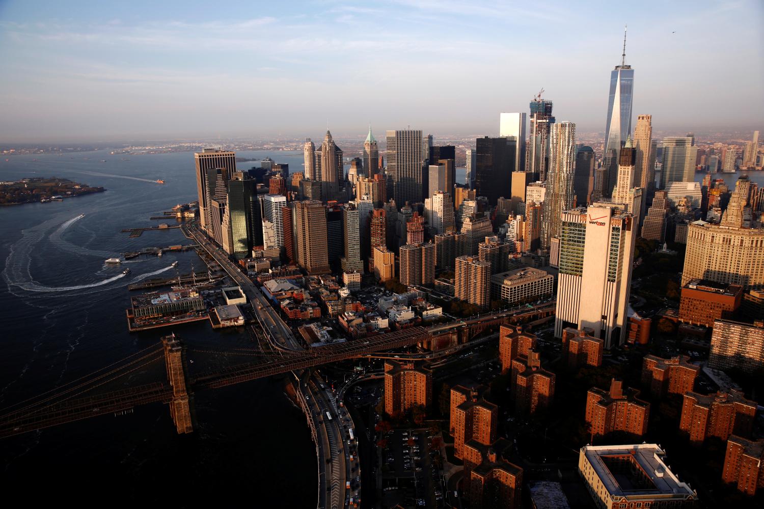 The rising sun lights the Brooklyn Bridge and One World Trade in the Manhattan borough of New York