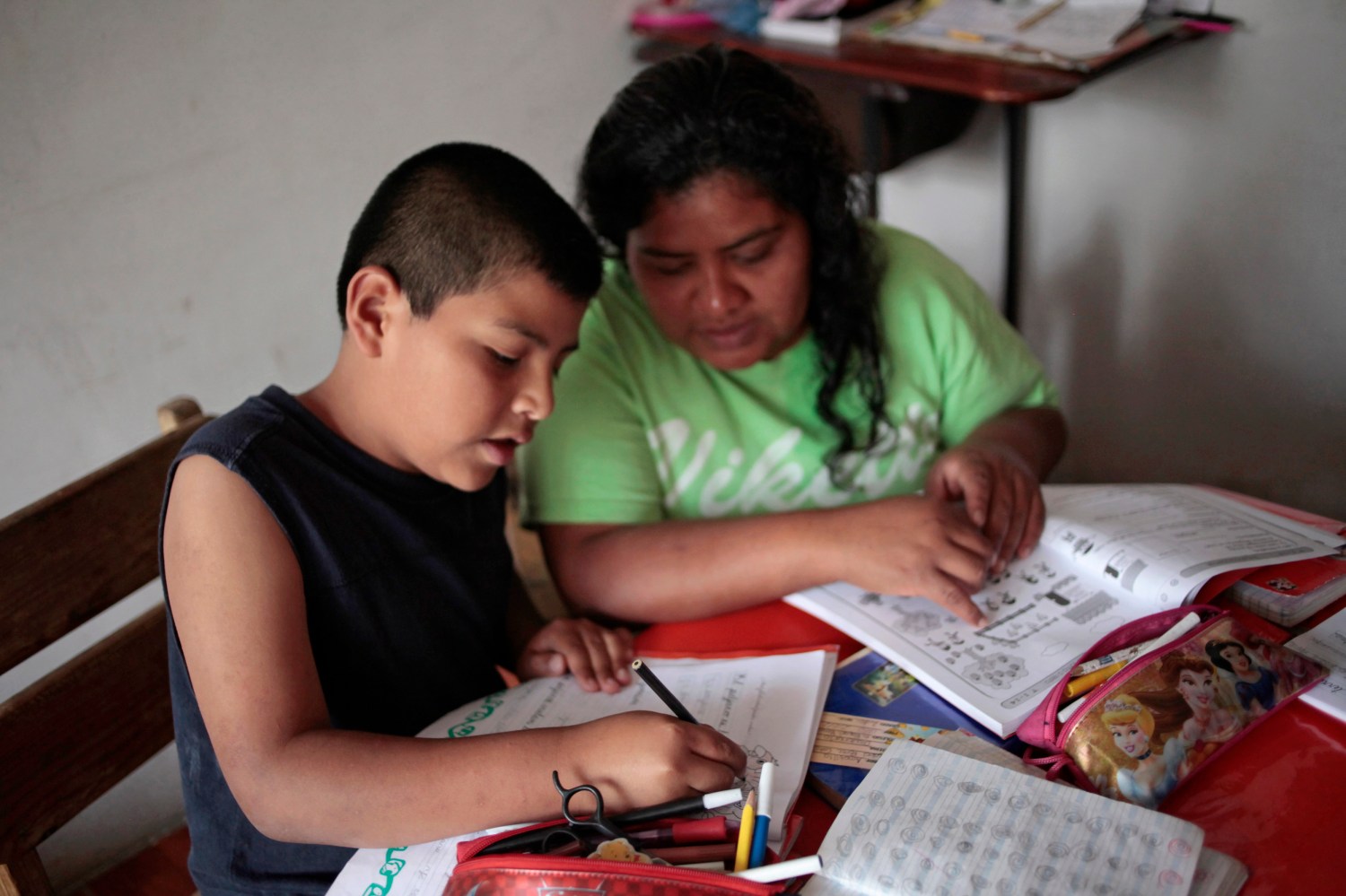Catalan helps her son, born in the U.S., with his homework at their home in San Jose Calderas