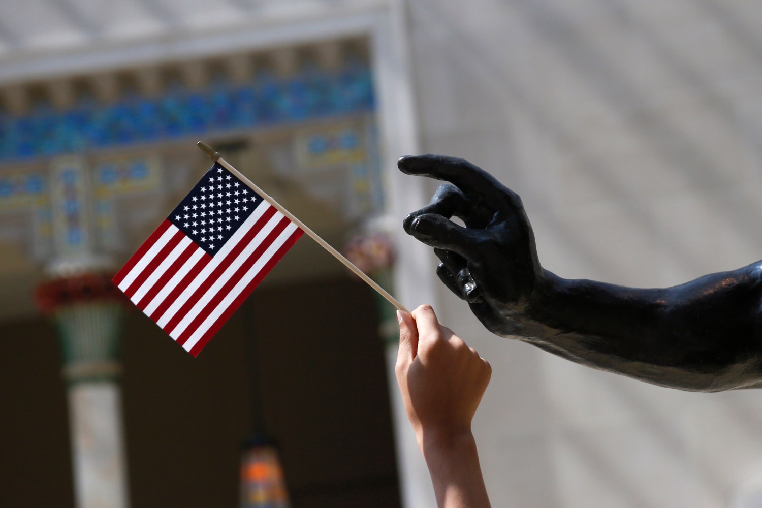 A girl holds a U.S. flag next to a sculpture after a naturalization ceremony at The Metropolitan Museum of Art in New York July 22, 2014. Seventy-five people from 42 countries became American citizens at an event held by U.S. Citizenship and Immigration Services (USCIS) at the Museum.