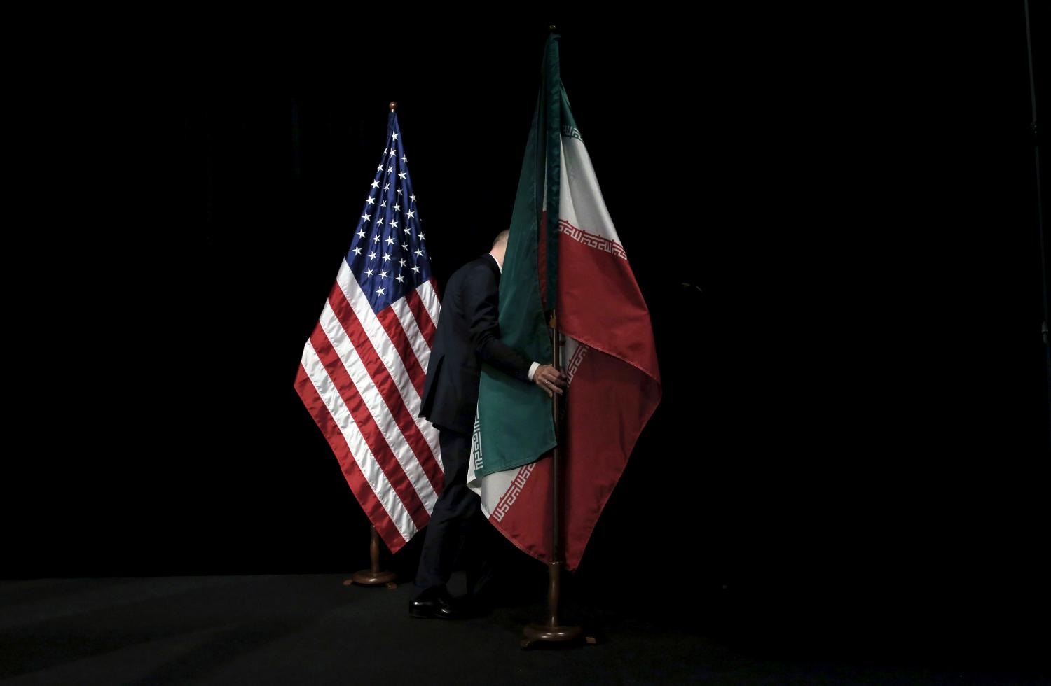 A staff member removes the Iranian flag from the stage after a group picture with foreign ministers and representatives of the U.S., Iran, China, Russia, Britain, Germany, France and the European Union during the Iran nuclear talks at the Vienna International Center in Vienna, Austria July 14, 2015. To match Analysis USA-ELECTION/IRAN REUTERS/Carlos Barria/File Photo - RTX2STPR