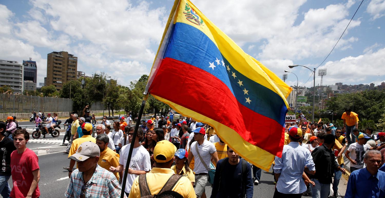 Opposition supporters holding a Venezuelan flag protest against Venezuela's President Nicolas Maduro's government during a rally in Caracas, Venezuela April 1, 2017. REUTERS/Carlos Garcia Rawlins - RTX33OG1