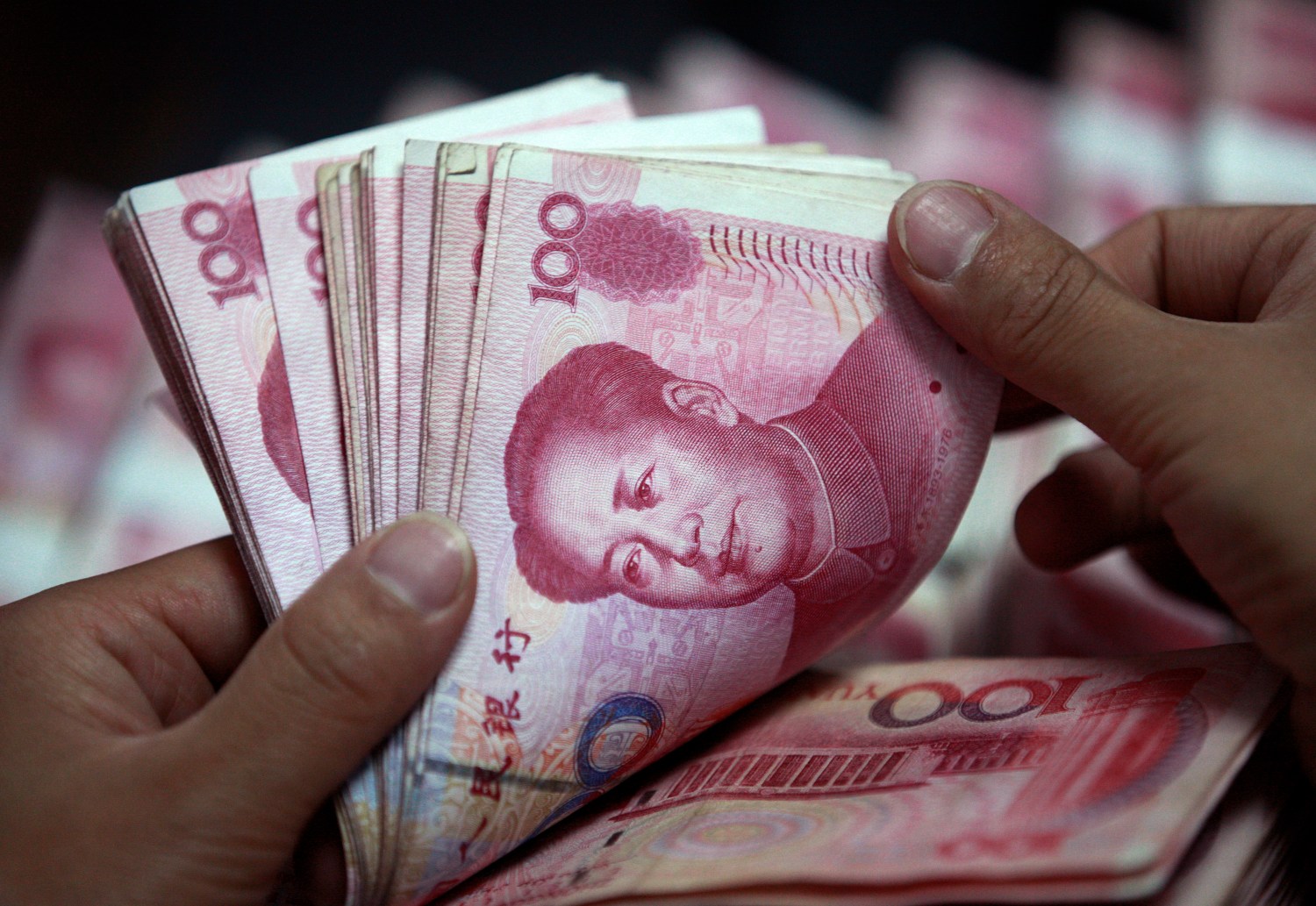 A bank clerk counts Chinese yuan