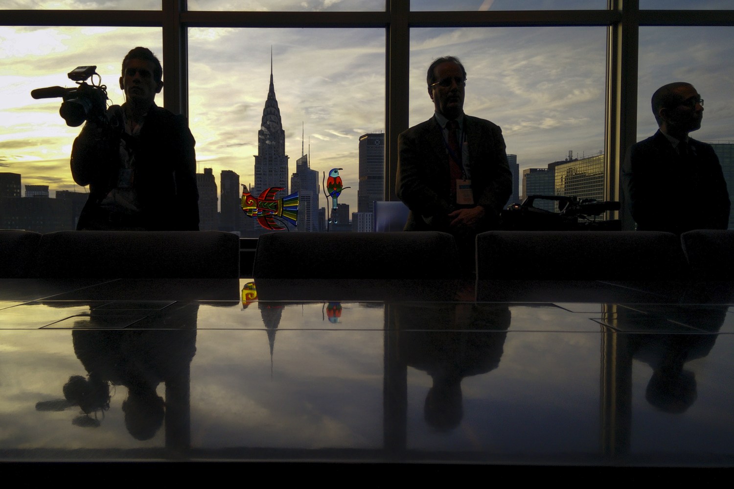 Media members are reflected in a board room table in the United Nations Secretary General's office.
