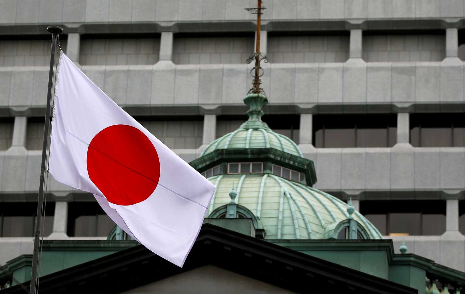 A Japanese flag flutters atop the Bank of Japan building.