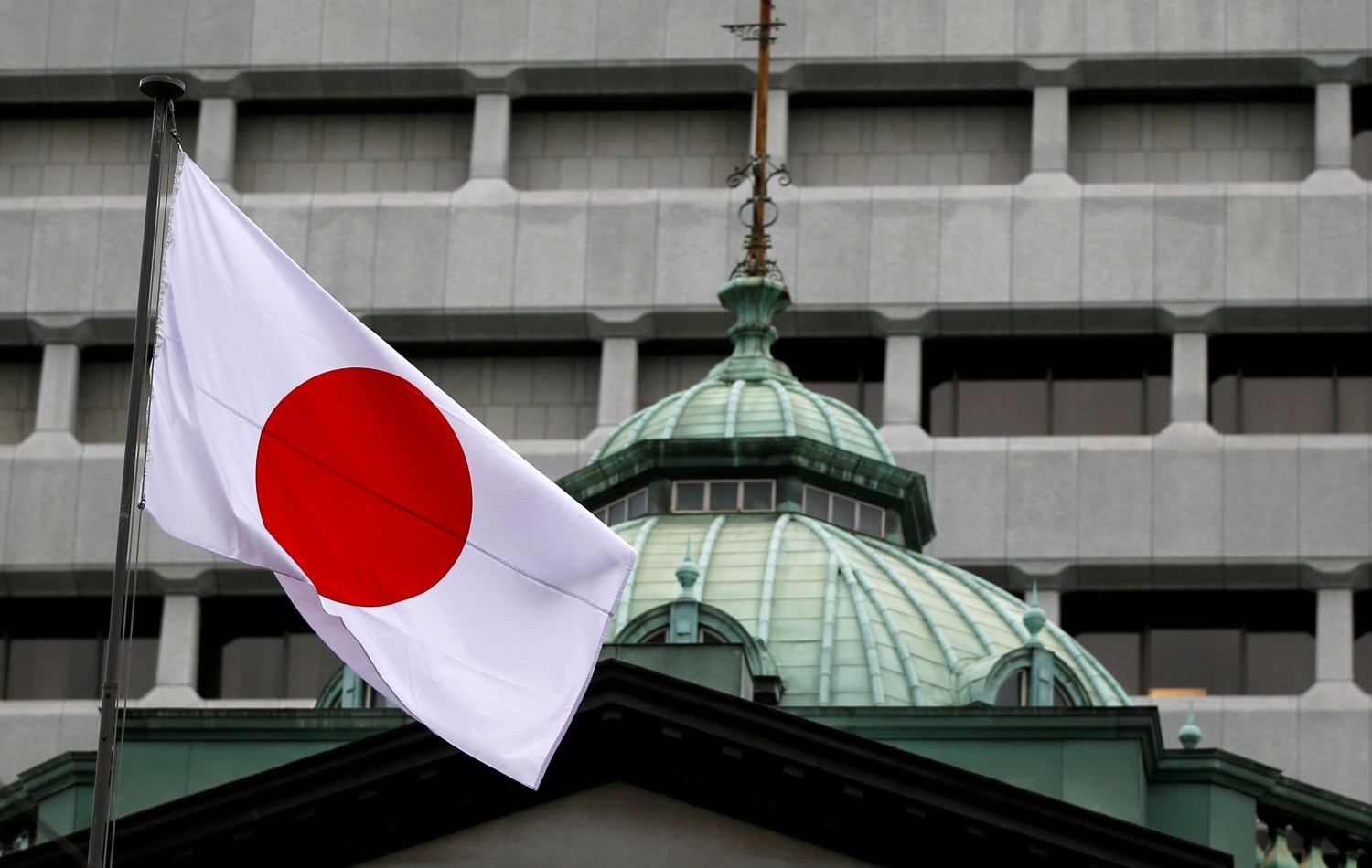 A Japanese flag flutters atop the Bank of Japan building.