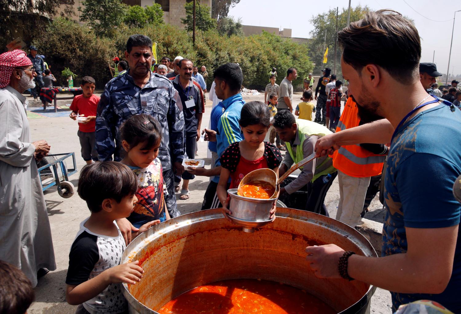 Residents receive food at a distribution point after the end of the battles between the Iraqi forces and Islamic State militants at Tayaran district in western Mosul