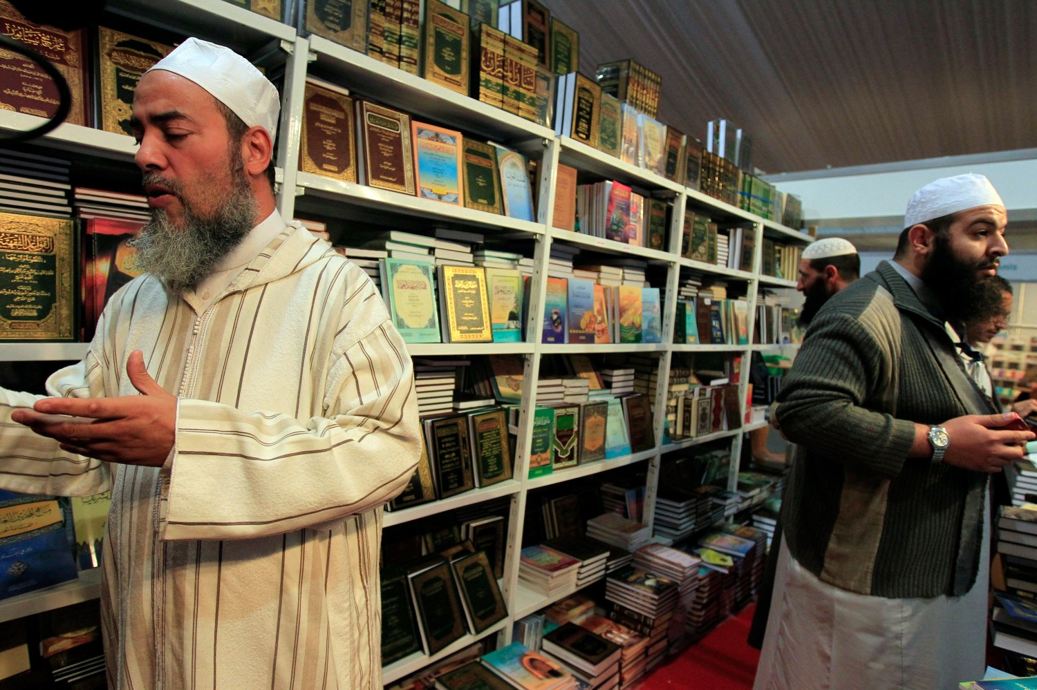 Sheikh Chemseddine Bouroubi (L), a well-known imam who follows a traditional Algerian school of Islam, reads a religious book at a Salafist stand during the 15th International Book Fair (SILA) in Algiers October 29, 2010. Algeria is cracking down on imports of books preaching the ultra-conservative Salafist branch of Islam, officials and industry insiders say, in a step aimed at reining in the ideology's growing influence. Salafism is a school of Islam that has its roots in Saudi Arabia and emphasises religious purity. Its followers reject the trappings of modern life, including music, Western styles of dress and taking part in politics. Picture taken October 29, 2010. To match Feature ALGERIA-RELIGION/BOOKS REUTERS/Zohra Bensemra (ALGERIA - Tags: EDUCATION SOCIETY RELIGION) - RTXV0GL